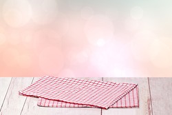 Empty table product. Closeup of a empty red checkered tablecloth or napkin on a rustic bright table over abstract pastel pink background. Template for your food and product display montage.