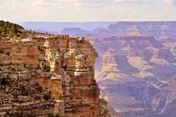 Tourist viewpoint and rockwalls of the South rim of the Grand Canyon with beautiful long sight view in the background.