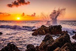 Waves splashing on rocks in the sunset. Sunset over the ocean with breaking waves. Rocks in the sea. Beautiful landscape of Tenerife with sunset. Playa de las arenas beach, Canary Islands Spain