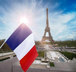 Flag of France is on background of the Eiffel Tower, blue sky, clouds and sun. Paris.  French flag is a tricolour flag with three vertical bands coloured blue, white, and red.