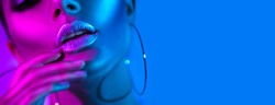 High Fashion model metallic silver lips woman in colorful bright neon blue and purple lights posing in studio, beautiful girl, trendy glowing make-up, colorful make up. Glitter Vivid neon makeup