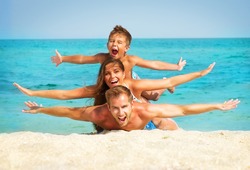 Happy Young Family with Little Kid Having Fun at the Beach. Joyful Family. Travel and Vacation