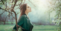 Beauty young woman enjoying nature in a garden, Happy Beautiful brunette girl in foggy Garden with trees. Person outdoors. Fashion model portrait