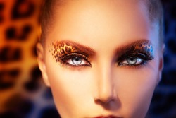 Beauty Fashion Model Girl with Holiday Leopard Makeup. Golden Wild Cat Eyes Make-up Eyeshadow. Beautiful Woman Face with Perfect skin. Animal Make up