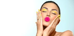 Beauty model girl with fashion make-up, Bright yellow eye line and nails, trendy manicure. Eye make-up creative ideas. Summer makeup. Kiss gesture. Beautiful young woman portrait. Face closeup