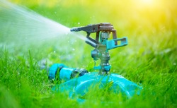 Sprinkler head watering green grass lawn. Gardening concept. Smart garden activated with full automatic sprinkler irrigation system working in a green park. Water