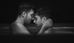 Gay couple relaxing in swimming pool. LGBT. Two young men kissing and hugging. Black and white portrait. Young men romantic family in love. Happiness concept