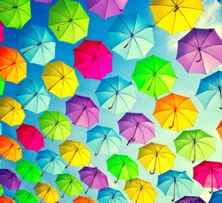Colorful umbrellas background. Colourful umbrellas urban street decoration. Hanging Multicoloured umbrellas over blue sky. Bright Colors backdrop