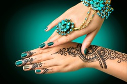 Woman Hands with black mehndi tattoo. Hands of Indian bride girl with black henna tattoos. Hand with perfect turquoise manicure and national Indian jewels. Fashion. India