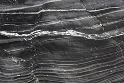 An abstract background image of the undulating layers of slate and marble on a geological cliff face