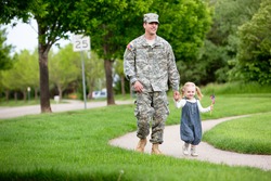 Handsome American Soldier in uniform having fun with his 2 year old daughter