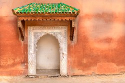 Typical decorated Moroccan door with green roof and ethnic handmade decoration.  
Rough wall with small multicolor port entrance in Arabic style decoration. Concept of 
freedom to travel around world.