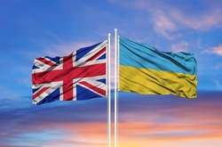 Ukraine and United Kingdom two flags on flagpoles and blue sky