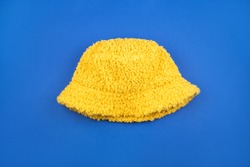 Cozy and bright yellow wool plush panama isolated on blue background.
