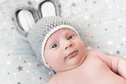 Cute little happy baby lies in a hare costume on a white background. newborn in a hat with ears on a white background