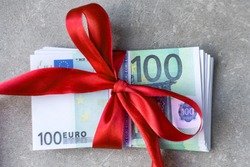 Hundred euro banknotes on a stack with red bow. Gift, bonus or reward concept