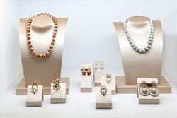 Set of luxury jewelry with precious gems and diamonds. Necklaces made of natural pearls on a stands. Women accessories
