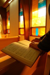 A hymn book inside a church being red by a woman.