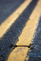Crack in a double yellow lined road with shallow depth of field.