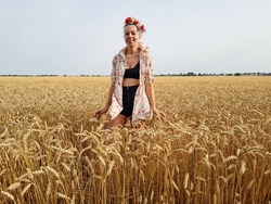 young woman posing in agriculture rye or barley or wheat field. girl wearing flower wreath on head. nature lover. summer wallpaper.