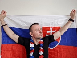 attractive man posing near white background with slovak flag. boy fanning or cheering to his national hockey team. ice hockey world championships.