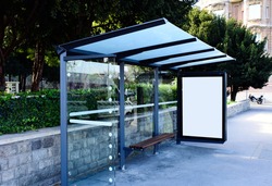 composite image of bus shelter and white lightbox. transit stop. blank. glass structure. urban setting. city street background. asphalt sidewalk.blank poster ad commercial space. background for mockup