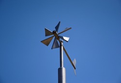 Anemometer wind speed indicator and measuring device. stainless steel tube post. wind vane, weather vane or wind cock. meteorological device. abstract low angle view. triangular blades. clear blue sky