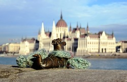 small bronze decorative snail figure sculpture along the shore of the Danube in Budapest with soft blurred background of the Parliament. art, travel and tourism concept. blue sky above. winter scene 