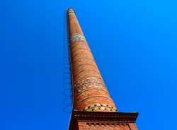 tall industrial brick chimney stack with steel access ladder and safety hoops. lightning rod and grounding device on the side. colorful artistic enamel mosaic tile inserts. industrial design concept