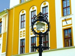 retro style street lantern. cast iron lamppost. colorful yellow stucco exterior wall background in old European town. old wood windows. urban street. travel and tourism concept. selective focus
