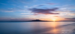 Sun rising over the Rangitoto Island at Milford Beach, Auckland.
