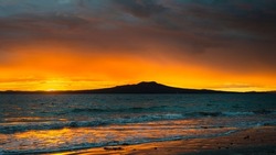 Sun rising over the Rangitoto Island, Milford Beach, Auckland.