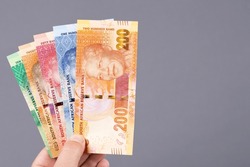 South African money - rand in the hand on a gray background