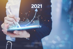 Businessman concept targeting business using laptop technology equipment is a 2021 concept showing the growth graph of trade, stock market and 2021 income.
