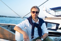 Handsome good looking mature man on the yacht. Portrait of successful man on sailing boat at sunset.