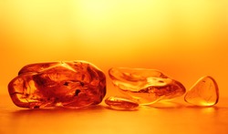 Chunks of amber in the yellow background light. An abstract pattern. Close up, blurred background. Selective focus, emphasis on the left stone. Negative space. Beautiful background, wallpaper.