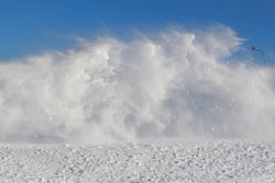 Vortexes of snow during the blizzard on blue sky background in the region of the far North. The theme of a natural disaster and the harsh polar climate. Typical picture of a northern winter. 

