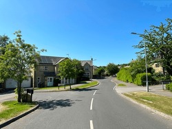 View toward, Thurlestone Court, with a tranquil setting of, trees, hedgerow, and houses in, East Morton, UK