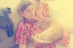 Man lying on the sofa and and on his belly lying a cat. - instagram style