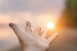 Human hand reaching for the sun