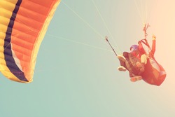 Two people are flying on a paraglider in the sky. Toned
