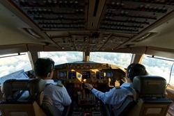 Asian two pilots were flying the commercial airplane. Seen from inside cockpit that can see cloud and sky through the window and all inside the cockpit. Real aviation concept.