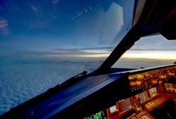The view from commercial airplane, seen from captain seat in cockpit in the evening twilight during flying above the cloud over the ocean.