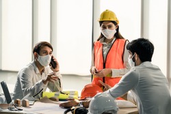 Group of building architect construction engineer have meeting and brainstorm together on table discussing about new project, teamwork talk with colleague. Members wear face mask prevent covid19 virus