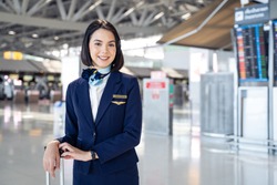 Portrait of beautiful Caucasian flight attendant staff smiling and looking at camera with confidence face and happiness in airport terminal. Feeling welcome all customer or passenger to the airplane.