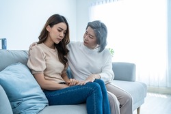 Asian loving elderly mother comforts upset daughter crying for problem. Caring Senior older mom support, consoling and understand empathy to stressed young woman in tears at home. Family relationship.