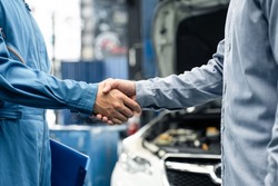 Asian automotive mechanic repairman handshake with client in garage. Vehicle service manager working in mechanics workshop, feel happy and success after check and maintenance car engine for customer.