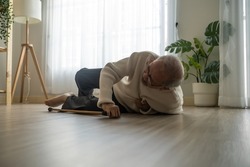Asian senior male falling on the ground while walk with walker at home. Elderly older mature grandfather having an accident after doing physical therapy alone after retirement in living room in house.