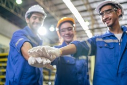 Group of young industrial people worker work in factory with happiness. Attractive manufactory engineer man and woman stack hands for motivate and work unity teamwork at manufacturing plant warehouse.