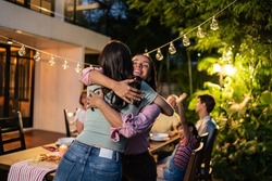 Young Asian woman visit the family during party outdoors in the garden. Attractive diverse group of people having dinner, eating foods, celebrate weekend reunion gathered together at the dining table
